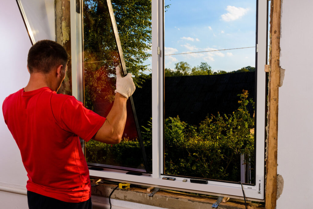 A contractor lifting a glass pane to fix a leaking window.