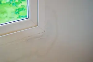 Leaking window in a home with visible water damage in the surrounding drywall.